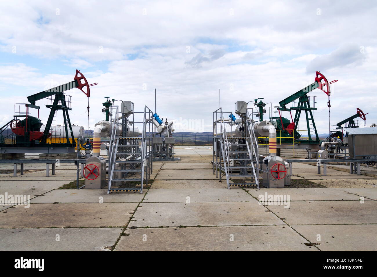 Grüne und rote Pferd pumpjack, Öl, Öl derrick Öl gut Pumpen mit dramatischen bewölkter Himmel Hintergrund Stockfoto