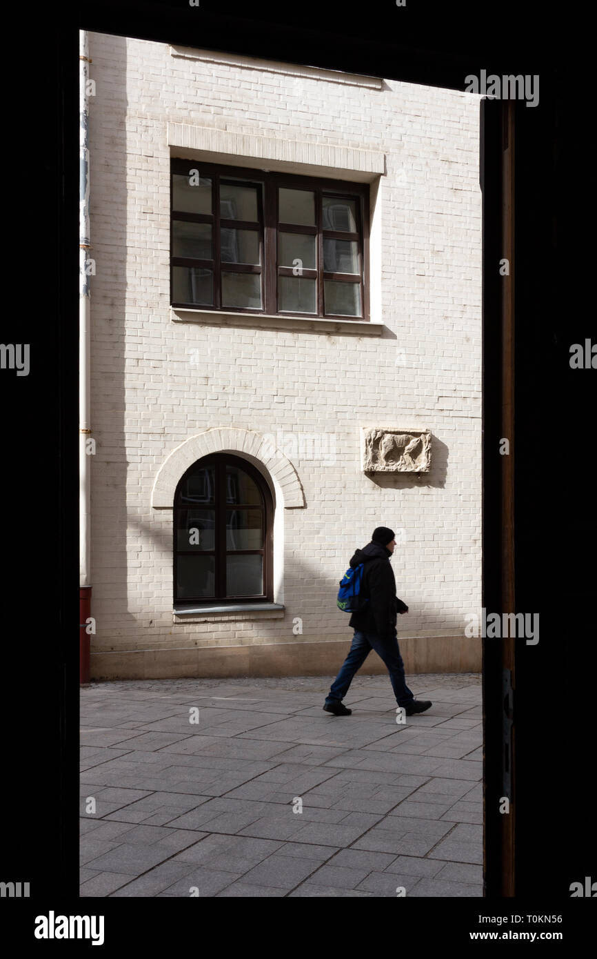 Blick von unter einem Gateway in die mittelalterliche Innenstadt von Sopron, Ungarn. Weiß gestrichene Mauer aus einem rekonstruierten Gebäude, mit einer alten Römischen r Stockfoto