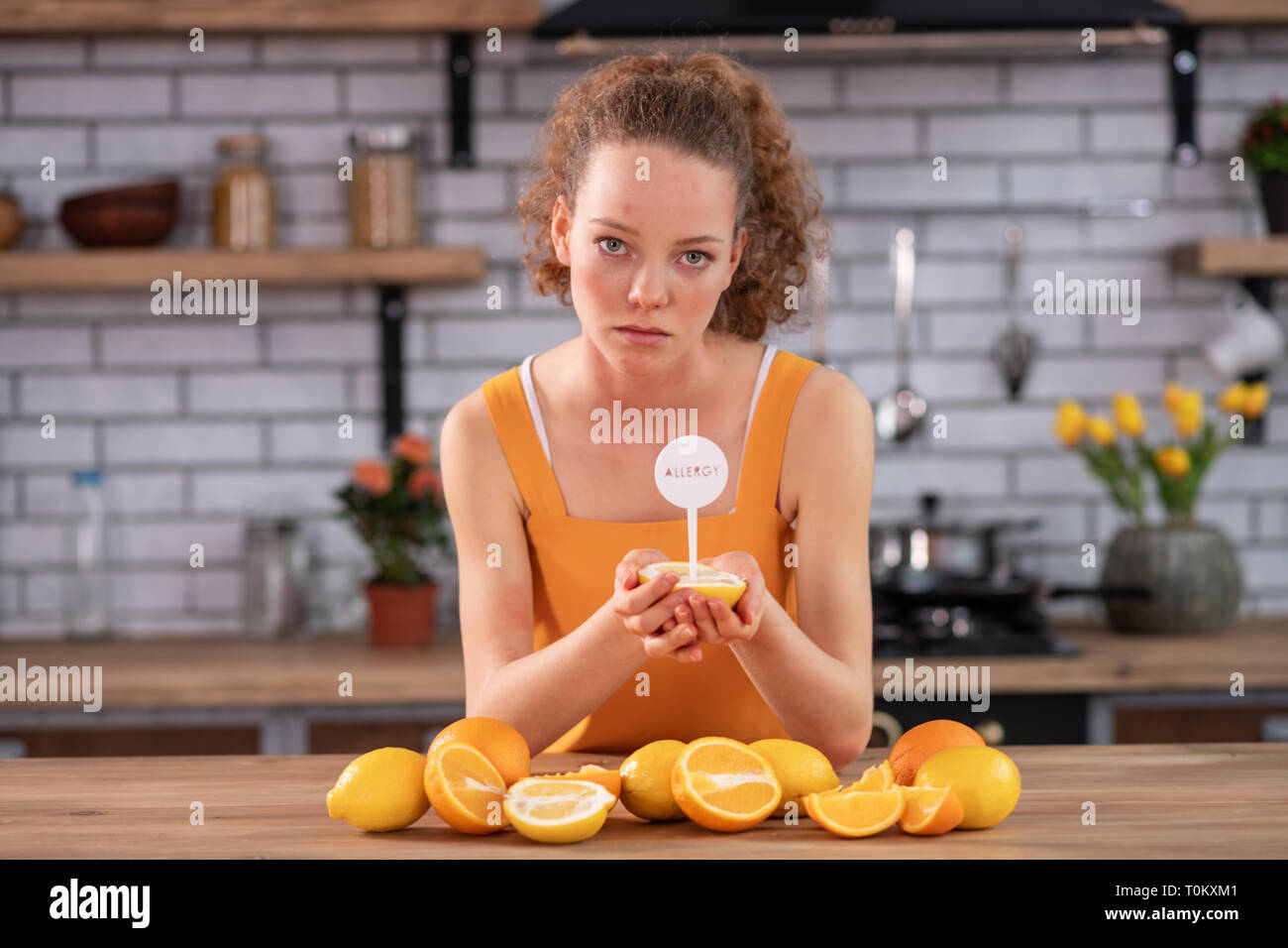Skinny Frau Schiefen am Küchentisch und die Hälfte der Zitrone Stockfoto