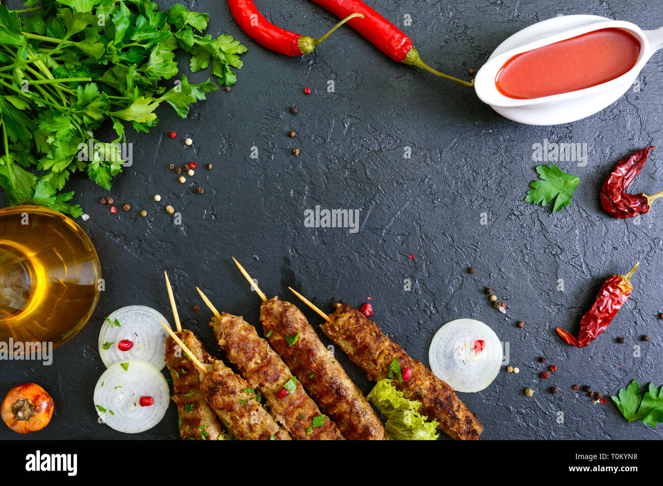 Lula Kebab ist eine traditionelle arabische Gericht. Fleisch Schaschlik auf Holzspieße, würzigen Tomatensauce auf schwarzem Hintergrund. Die Draufsicht, spase kopieren Stockfoto