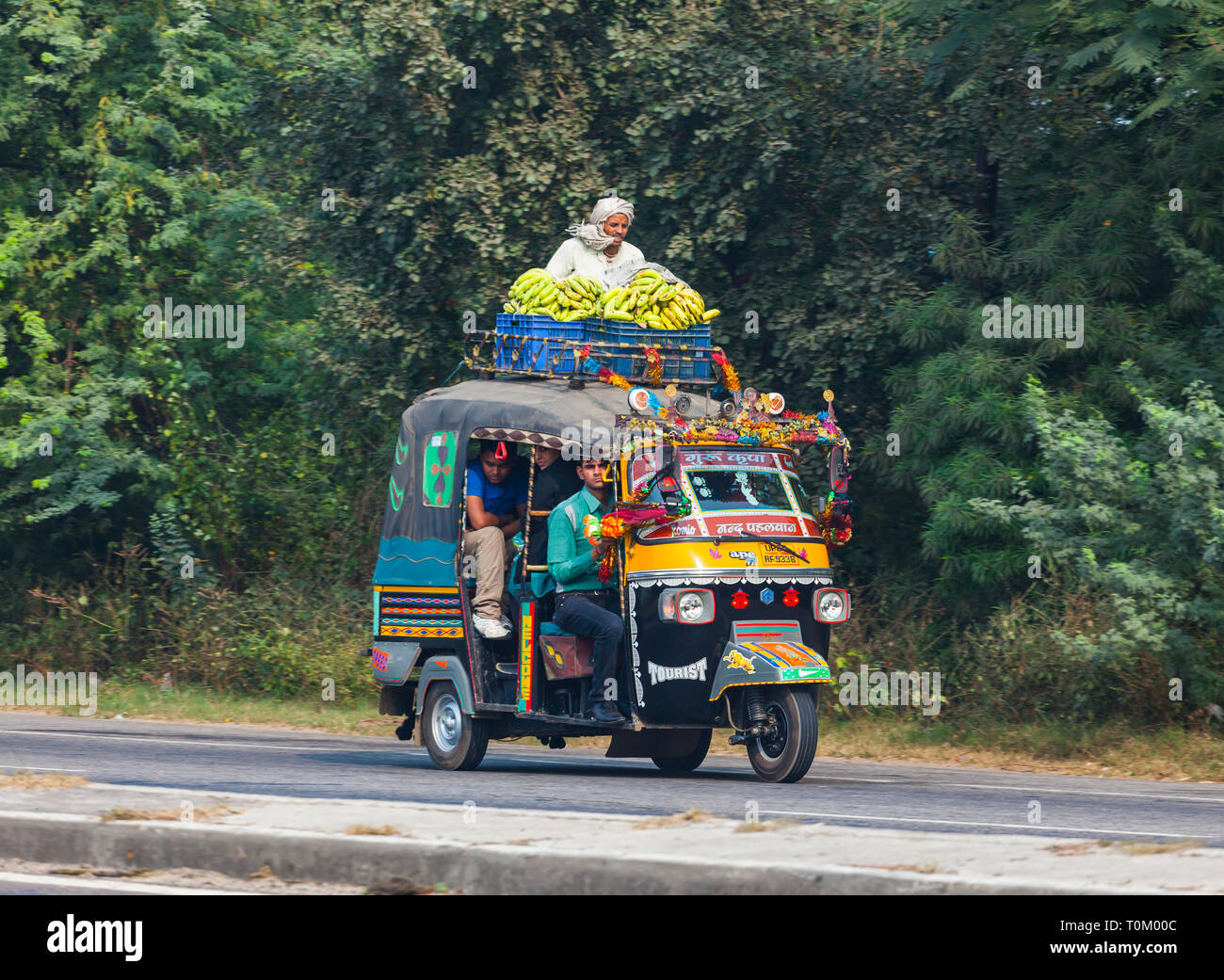 AGRA, INDIEN - November 15, 2012: Verkehr auf den Straßen von Indien. Große indische Familien reisen in ein kleines Auto. Indische Menschen und ihre bunten Kult Stockfoto