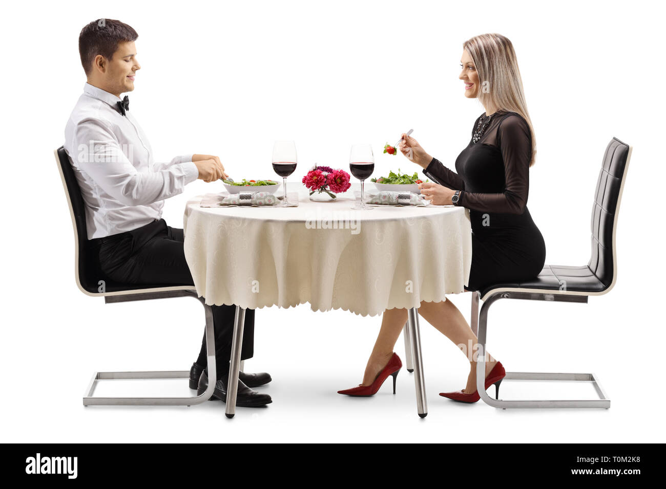 Volle Länge Profil Schoß eines jungen Paares in Salat und Wein in einem Restaurant auf weißem Hintergrund Stockfoto