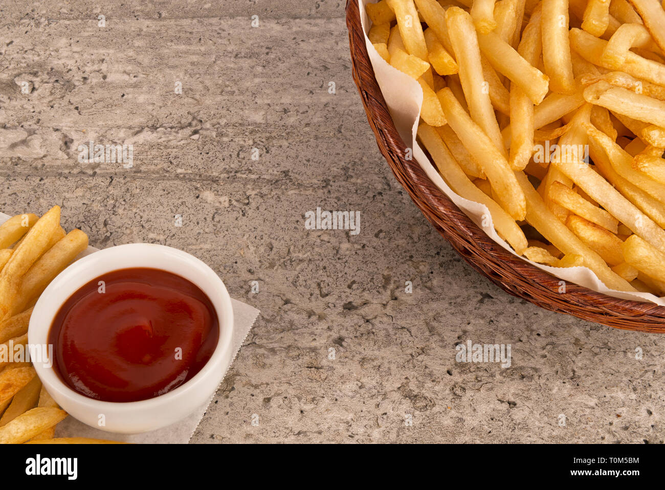 Warenkorb Pommes Frites mit Ketchup auf konkreten Hintergrund. Salz, Ketchup und Senf Flasche. Close Up. Stockfoto
