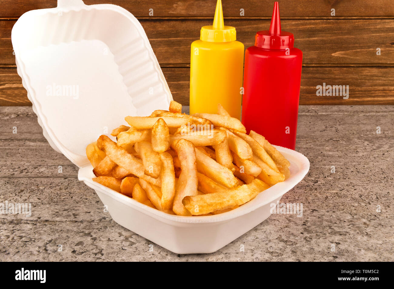 Pommes frites in takeout Container. Ketchup und Senf Flasche auf der Seite.  Close Up Stockfotografie - Alamy