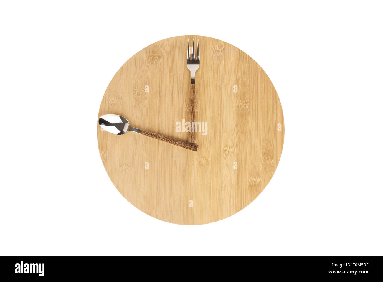 Gabel und Löffel entsorgt auf einem runden Holztafel, die Zeit für das Mittagessen als Uhr anzuzeigen. Stockfoto