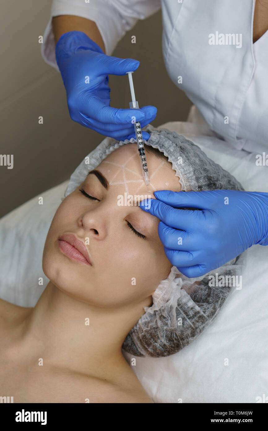 Ästhetische Kosmetologie. Facelift in Spa Salon. Kosmetikerin, Stirn Falten der Injektion Mädchen. Glättung von Falten nachahmen. Close-ups Stockfoto