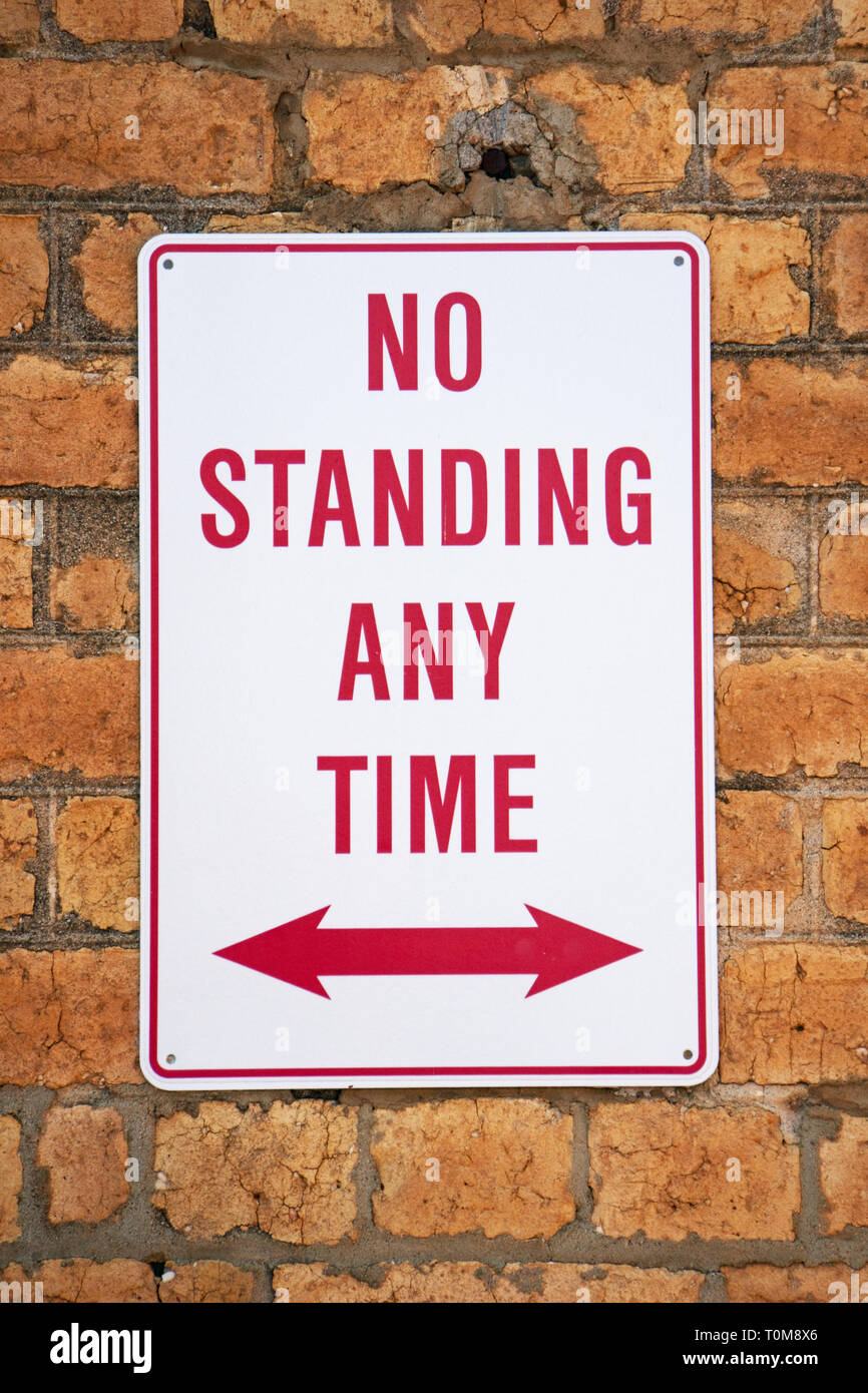 Australische signage zeigt eine Keine stehende Zeichen mit einer Ziegelwand Hintergrund. Zeichen rot und roter Richtungspfeil mit weißem Hintergrund. Stockfoto