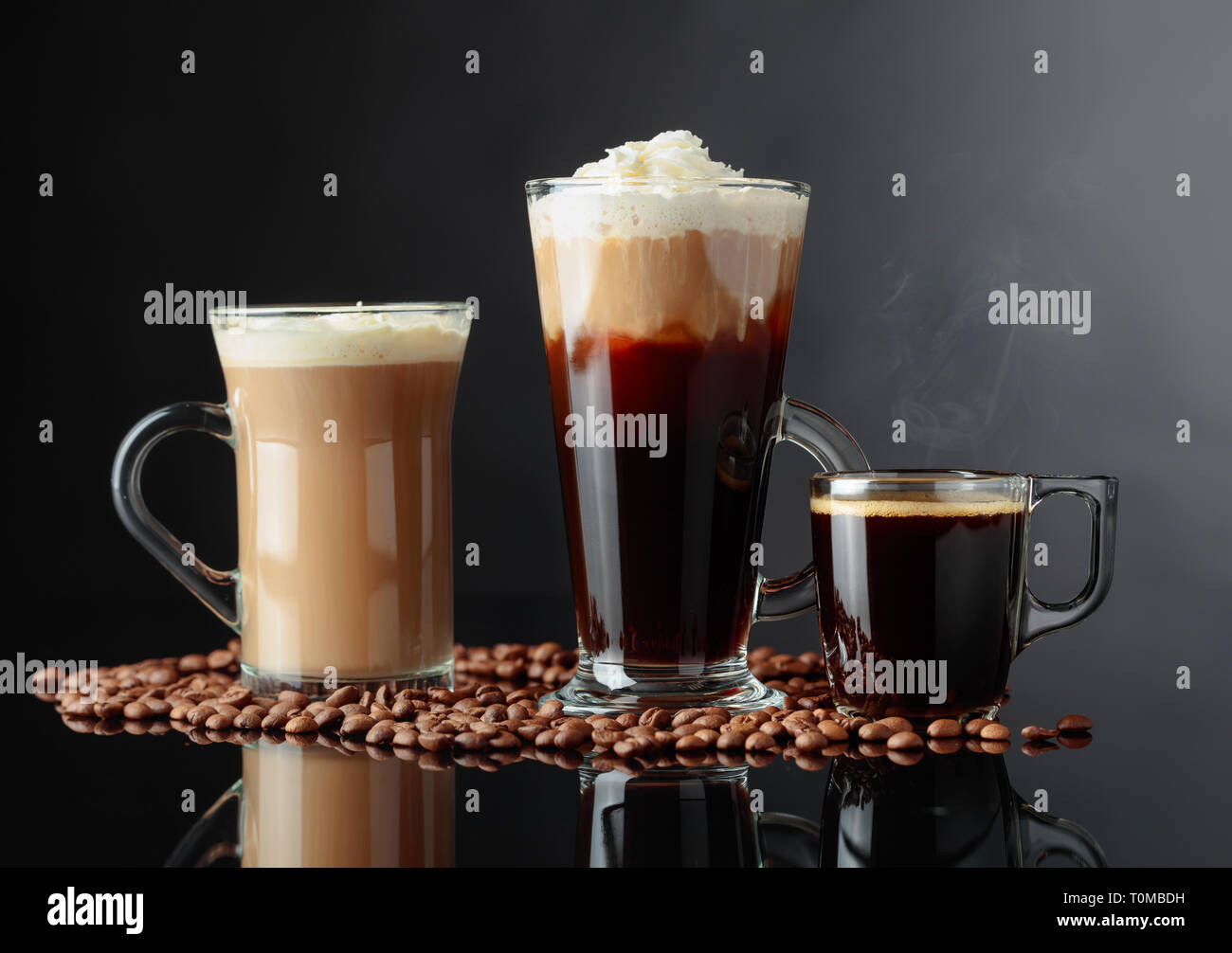 Latte, Irish Coffee und Espresso auf Schwarz reflektierenden Hintergrund mit Kaffeebohnen. Stockfoto