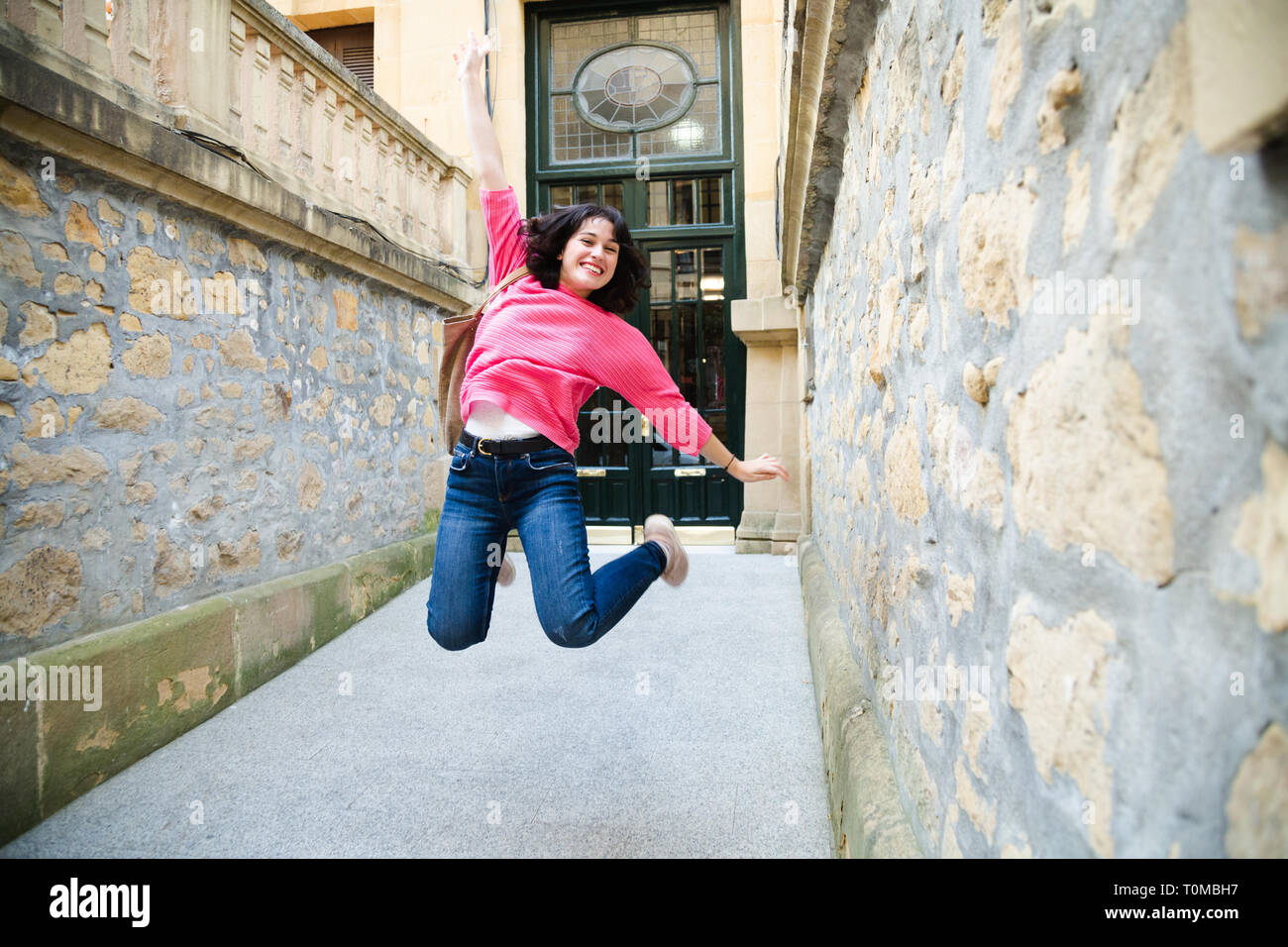 Glückliche junge Frau in rosa Pullover springen, wenn das Haus zu verlassen. Bei einigen Wegen der Bewegung Stockfoto