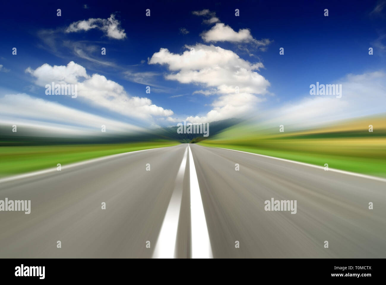 Straße inmitten grüner Felder mit Motion blur Effekt, blauen Himmel im Hintergrund Stockfoto