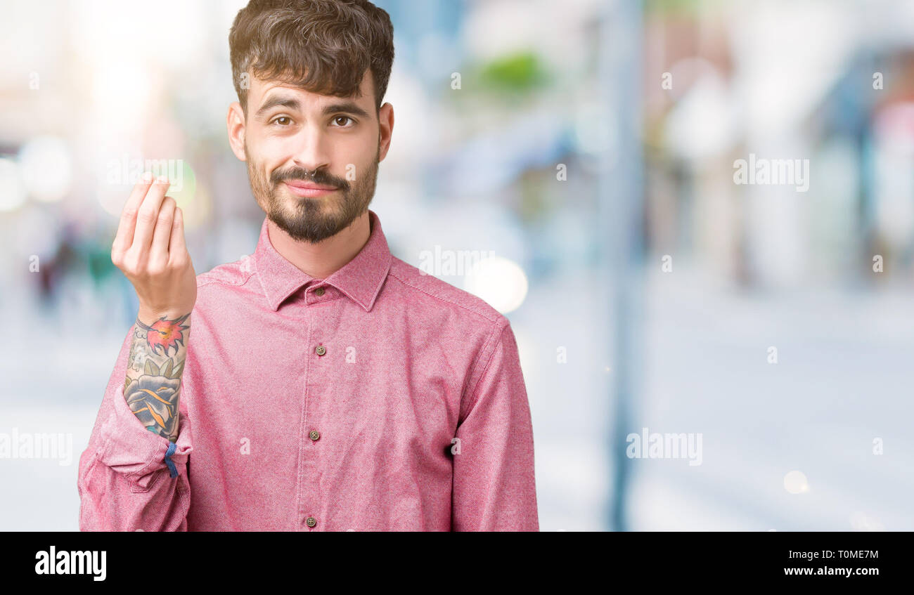 Jungen gutaussehenden Mann mit rosa Shirt über isolierte Hintergrund tun Italienische Geste mit der Hand und den Fingern zuversichtlich Ausdruck Stockfoto