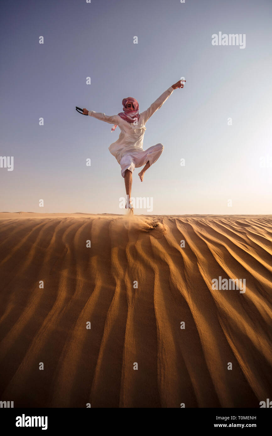 Ein saudischer Mann ist das Springen in Wüste, Saudi-Arabien Stockfoto