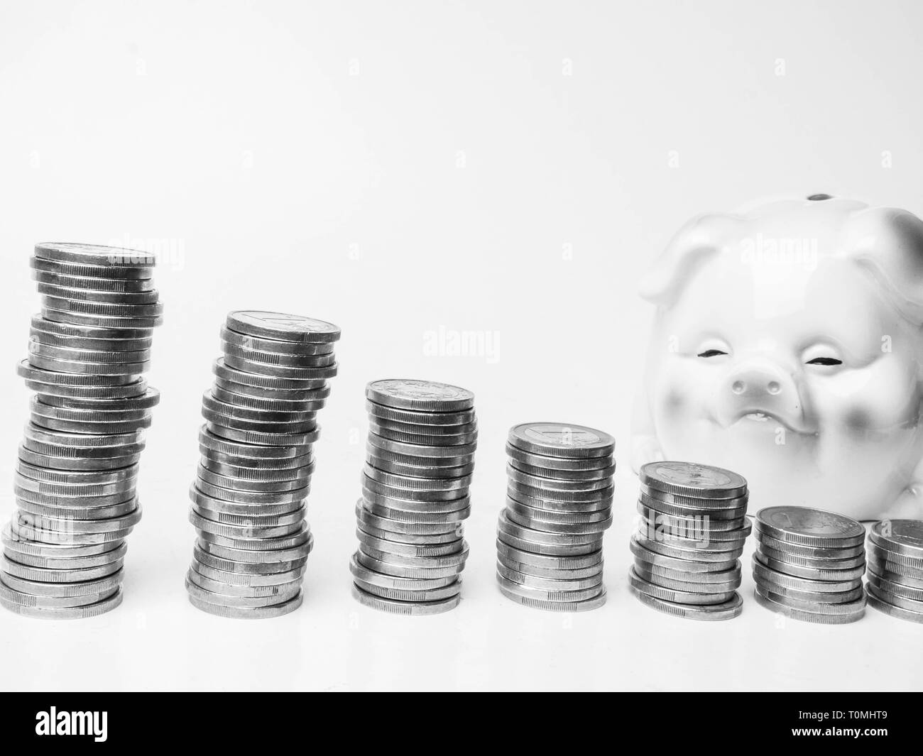Mini piggy Bank steht neben Münze Tower, Schwarzweiß, Kopieren Raum Stockfoto