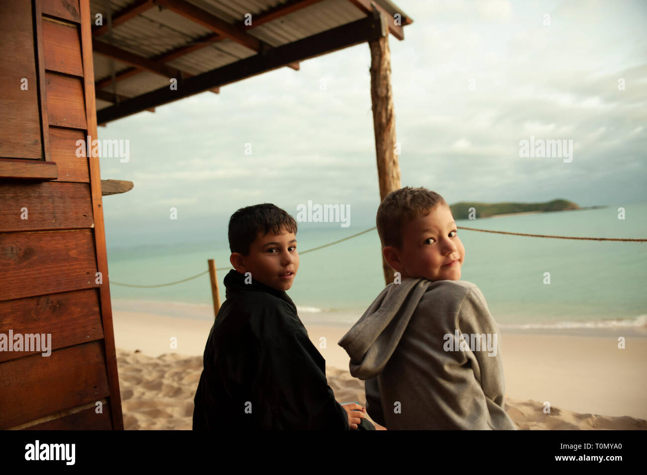 9 Jahr alt und 7 Jahre alten Jungen außerhalb eines Lean Beach Hut auf Putney Strand, Great Keppel Island, Queensland, Australien Stockfoto