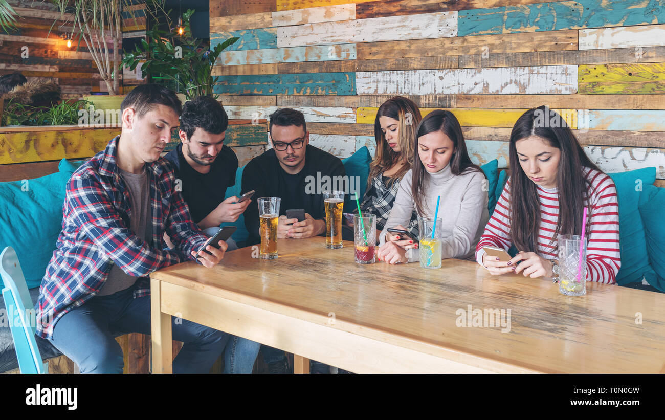 Eine Gruppe von Freunden im trendigen Pub ignorieren einander für Mobiltelefon Stockfoto