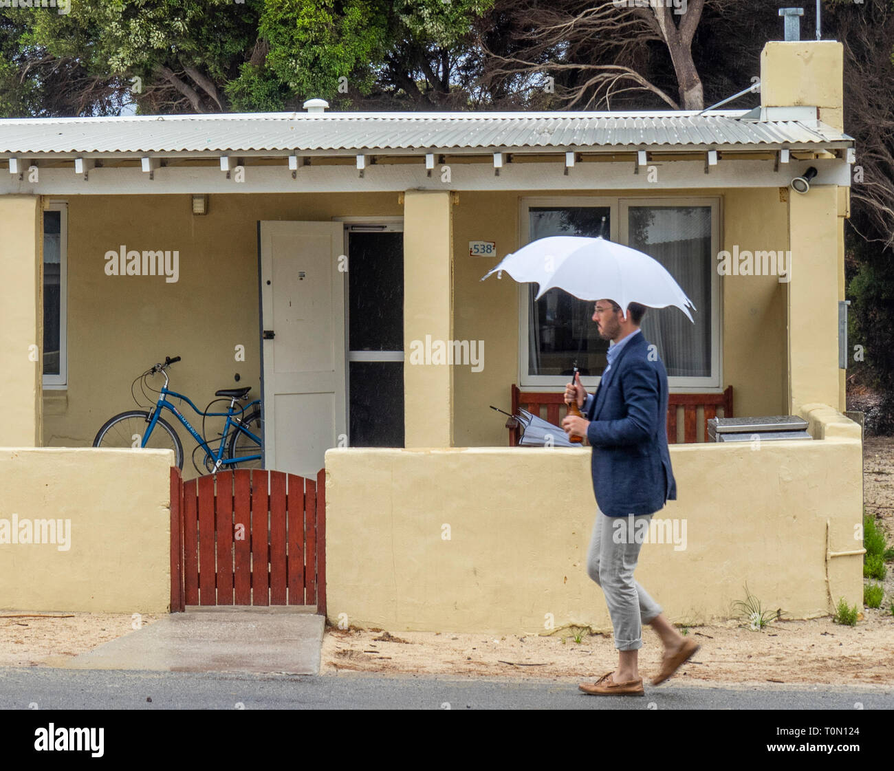 Kaukasische Mann Mit Einem Weissen Sonnenschirm Und Tragt Blaue Jacke Vorbei Gehen Ein Ferienhaus Auf Rottnest Island Wa Australien Stockfotografie Alamy