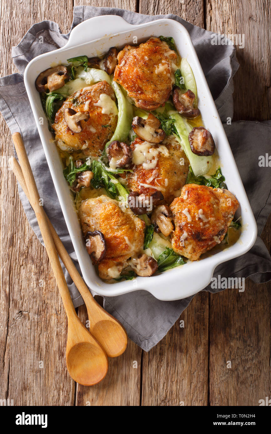 Hühnerkeule mit Baby Bok Choy, Shiitake Pilze und Käse Sauce in einem rustikalen Stil close-up auf dem Tisch. Senkrechte Draufsicht von oben Stockfoto