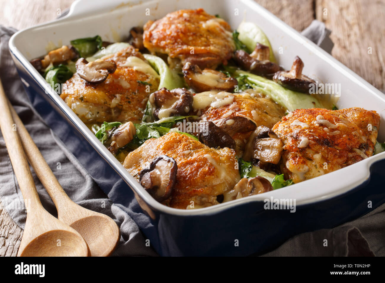 Gesundes Essen gebackene Hühnerkeule mit Baby Bok Choy, Shiitake Pilze und Käse Sauce in einem rustikalen Stil Nahaufnahme auf dem Tisch. Horizontale Stockfoto