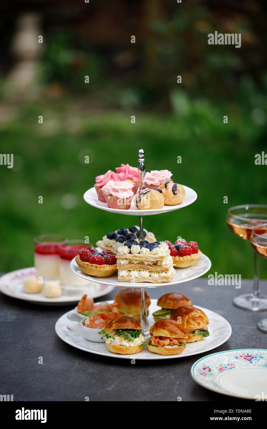 Nachmittagstee mit Mini brioche Kanapees und Auswahl an Süßigkeiten Stockfoto