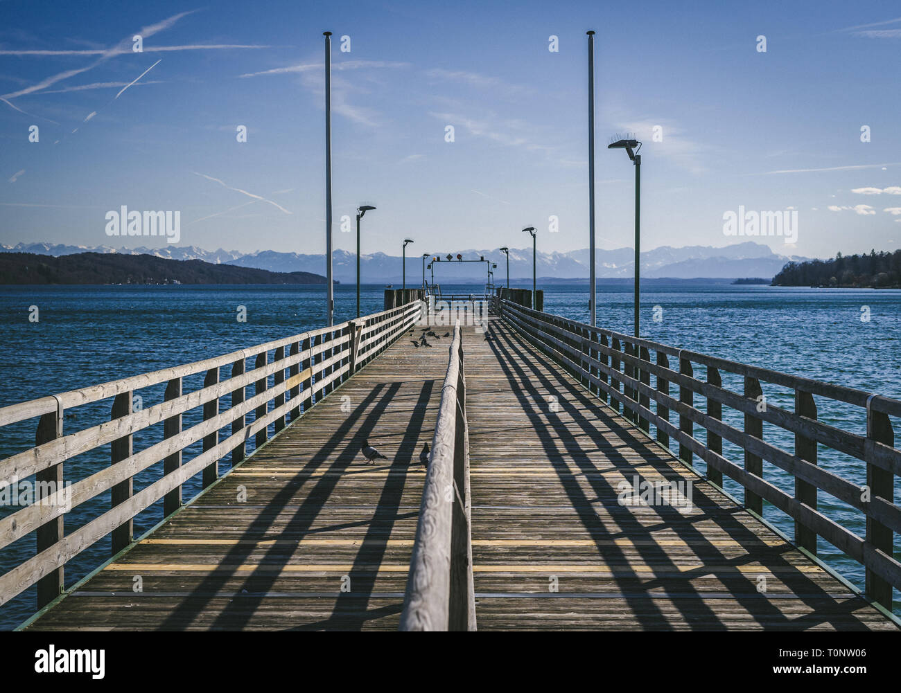 Pier ohne Menschen an einem sonnigen Tag mit den Alpen im Hintergrund am Starnberger See in der Nähe von München in Deutschland Stockfoto