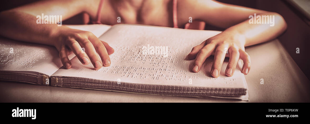 Blindes Mädchen mit beiden Händen in Blindenschrift lesen Stockfoto