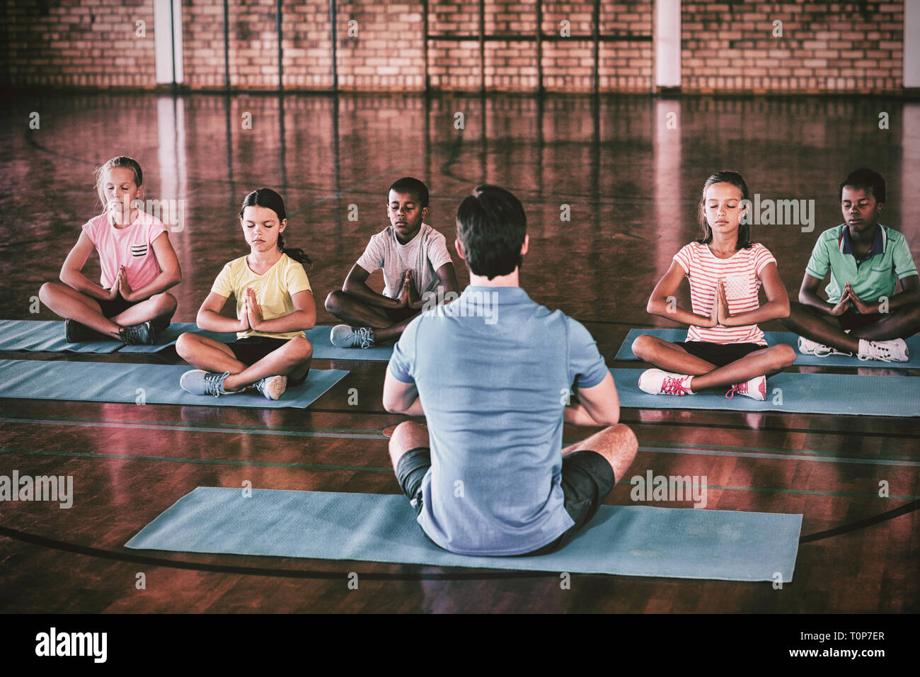 Schülerinnen und Schüler und Lehrer meditieren während Yoga-Kurs Stockfoto