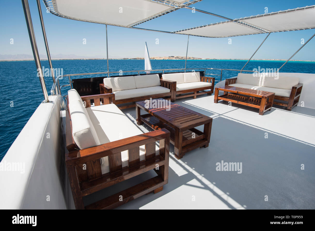 Hintere Sonnendeck einer großen Luxus-Motoryacht mit Sessel Sofa Tisch und tropischen Meer Blick Hintergrund Stockfoto