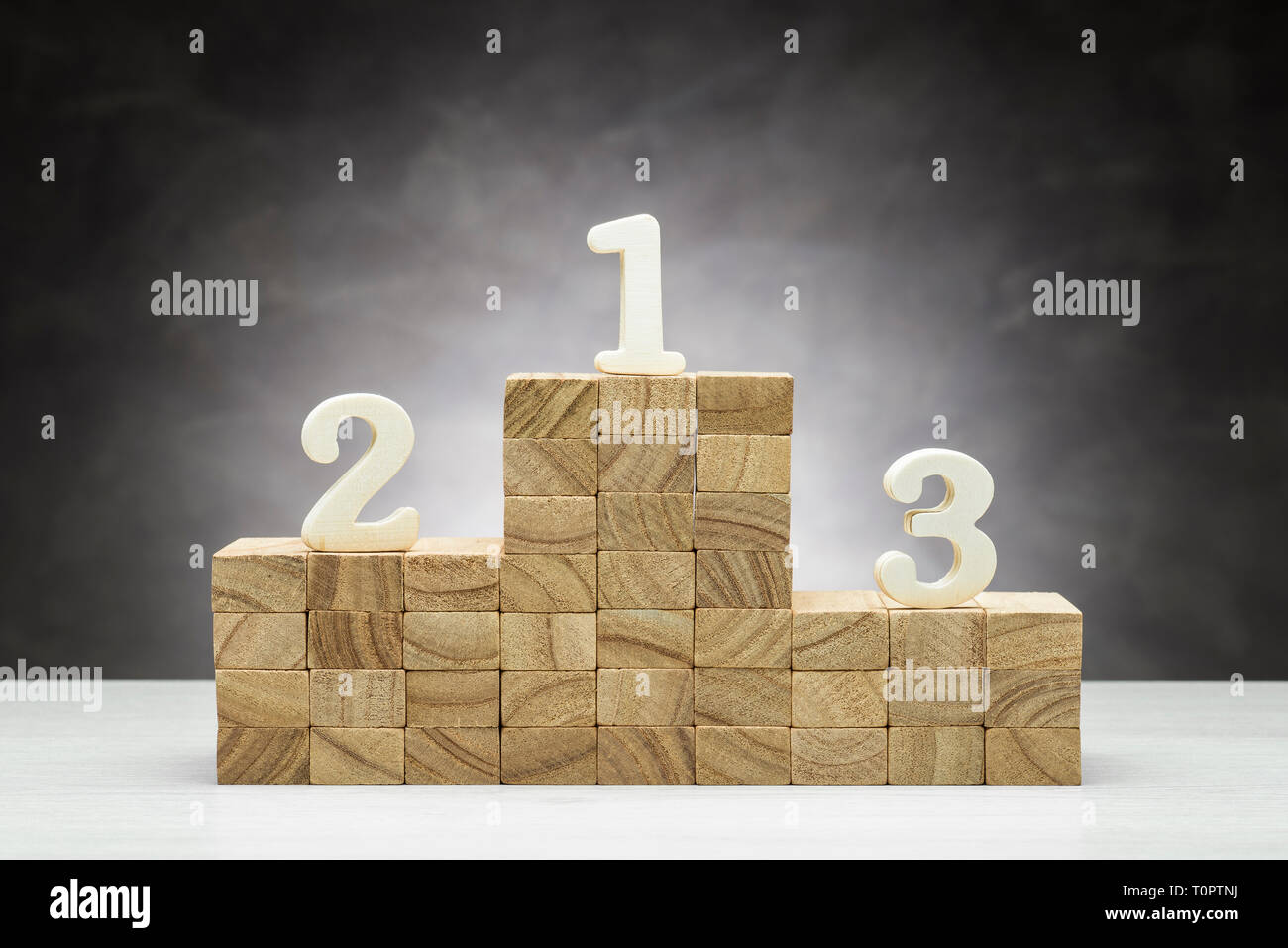 Konzept des Wettbewerbs. Holz- Podium auf grauem Hintergrund mit Zahlen. Stockfoto
