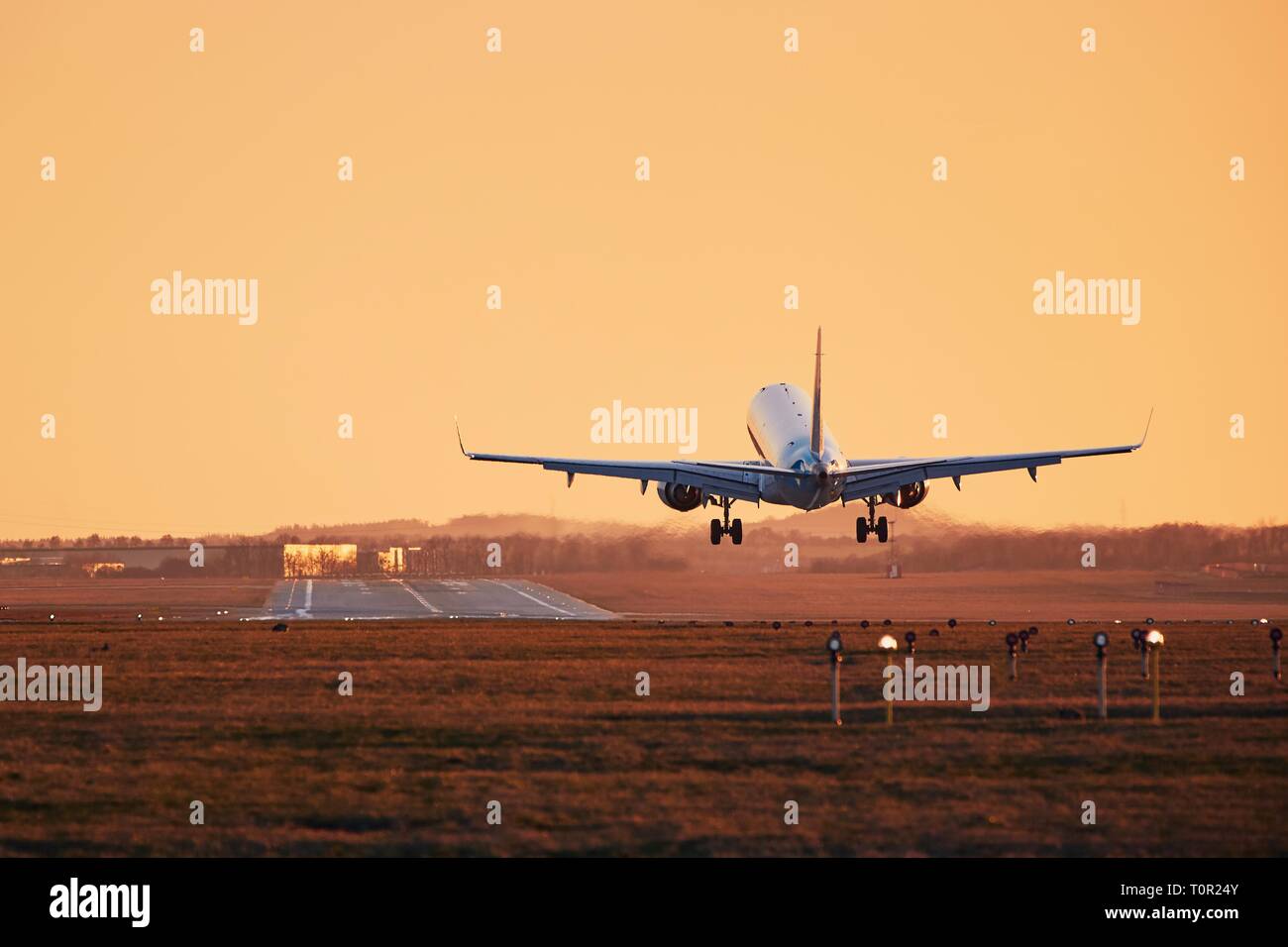Verkehr am Flughafen. Flugzeug Landung auf der Landebahn bei Sonnenuntergang. Stockfoto