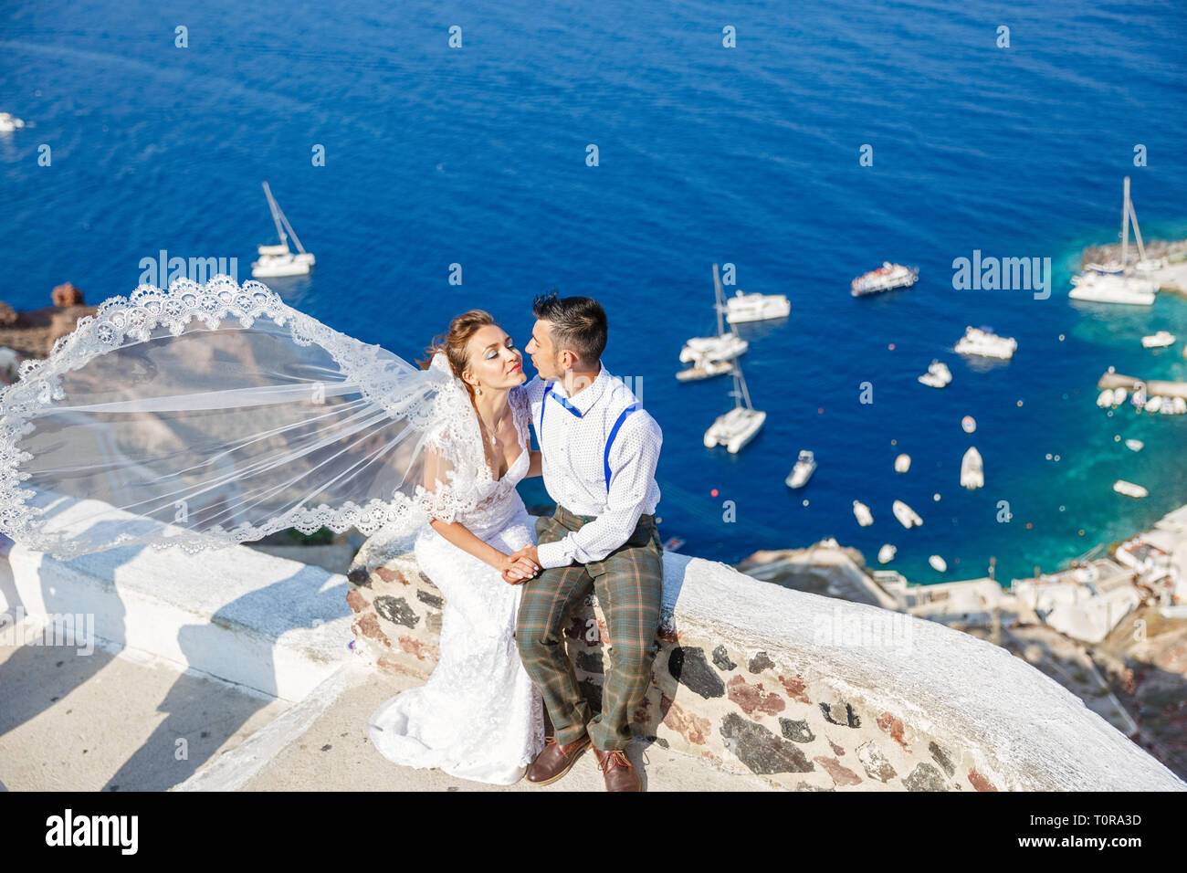 Bräutigam küsst die Braut, Schleier im Wind. Griechenland, Insel Santorini Stockfoto