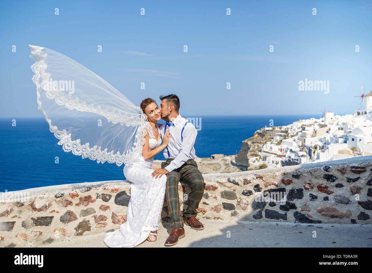 Bräutigam küsst die Braut, Schleier im Wind. Griechenland, Insel Santorini Stockfoto
