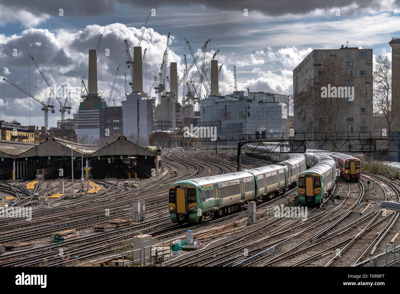 Der Zug der Südbahn nähert sich der Ebury Bridge bei der endgültigen Annäherung an den Bahnhof Victoria, mit dem Battersea Power Station in der Ferne London, Großbritannien Stockfoto