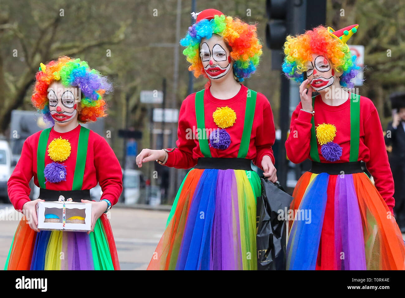 Orthodoxe jüdische Frauen sind als Clowns während des Festes von Purim auf den Straßen von Stamford Hill im Norden Londons gekleidet. Purim ist einer der unterhaltsamsten jüdischen Feiertage. Es erinnert an die Zeit, in der die jüdischen Menschen in Persien wurden von Massaker von Haman gespeichert. Es ist üblich, den Karneval - wie Feiern an Purim zu halten, und für Gruppen von Männern runde Besuch lokaler wohlhabende Männer zu gehen, sammeln für ihre Nächstenliebe. Stockfoto