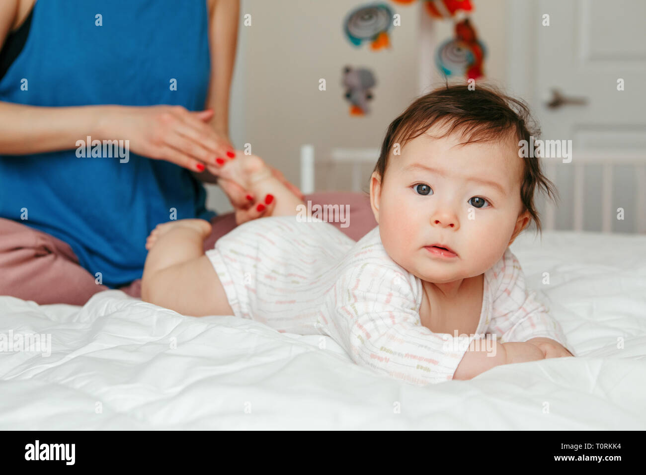 Portrait von cute adorable gemischten Rennen asiatischen Mutter mit neugeborenen Babys tun, Massage und körperlichen Übungen. Frühe Entwicklung und Gesundheit Lebensstil Stockfoto