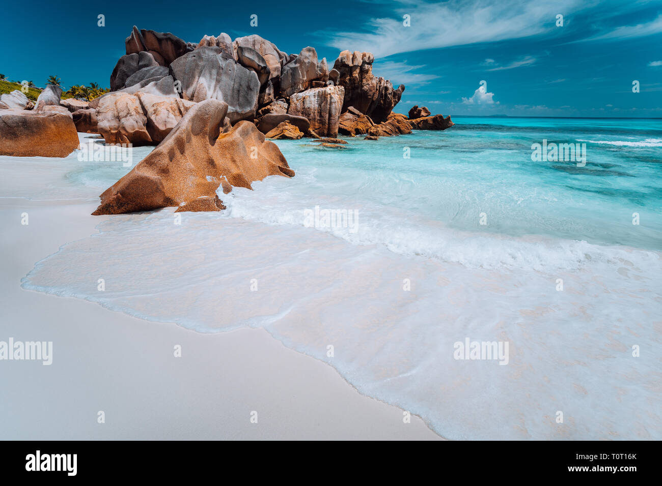 Granit Felsen, Geröll, perfekte weißer Sand, türkises Wasser, blauer Himmel. Paradise Beach Anse Cocos auf die Seychellen. Ferienhäuser Hintergrund Stockfoto