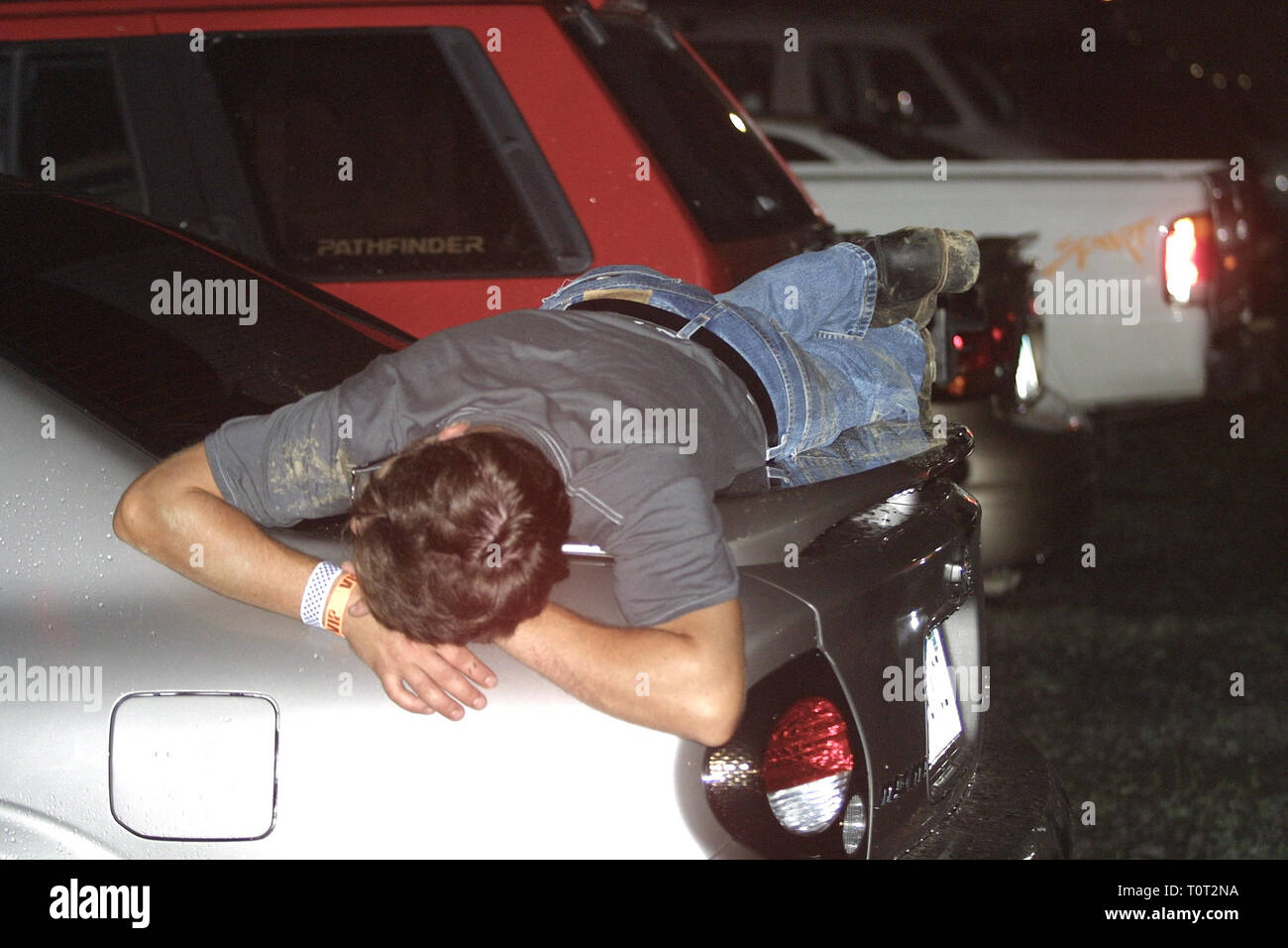 Ein Konzert Ventilator wird angezeigt, schlafen in den Kofferraum eines Autos außerhalb der Halle während einer "live"-Leistung. Stockfoto