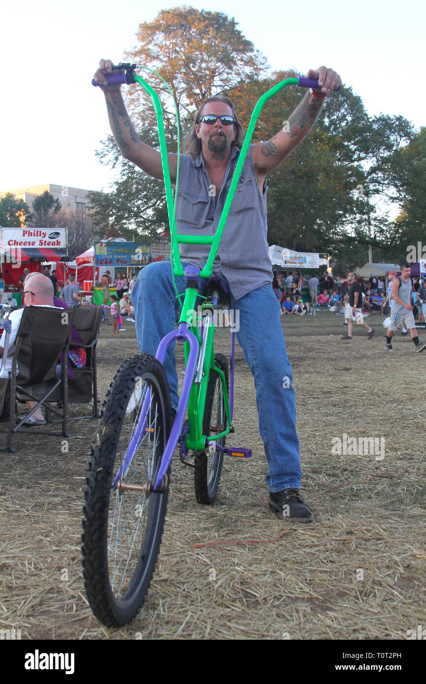 Dieses Konzert goer wird angezeigt für die Kamera auf seinem chopper Fahrrad an einer im Music Festival posieren. Stockfoto