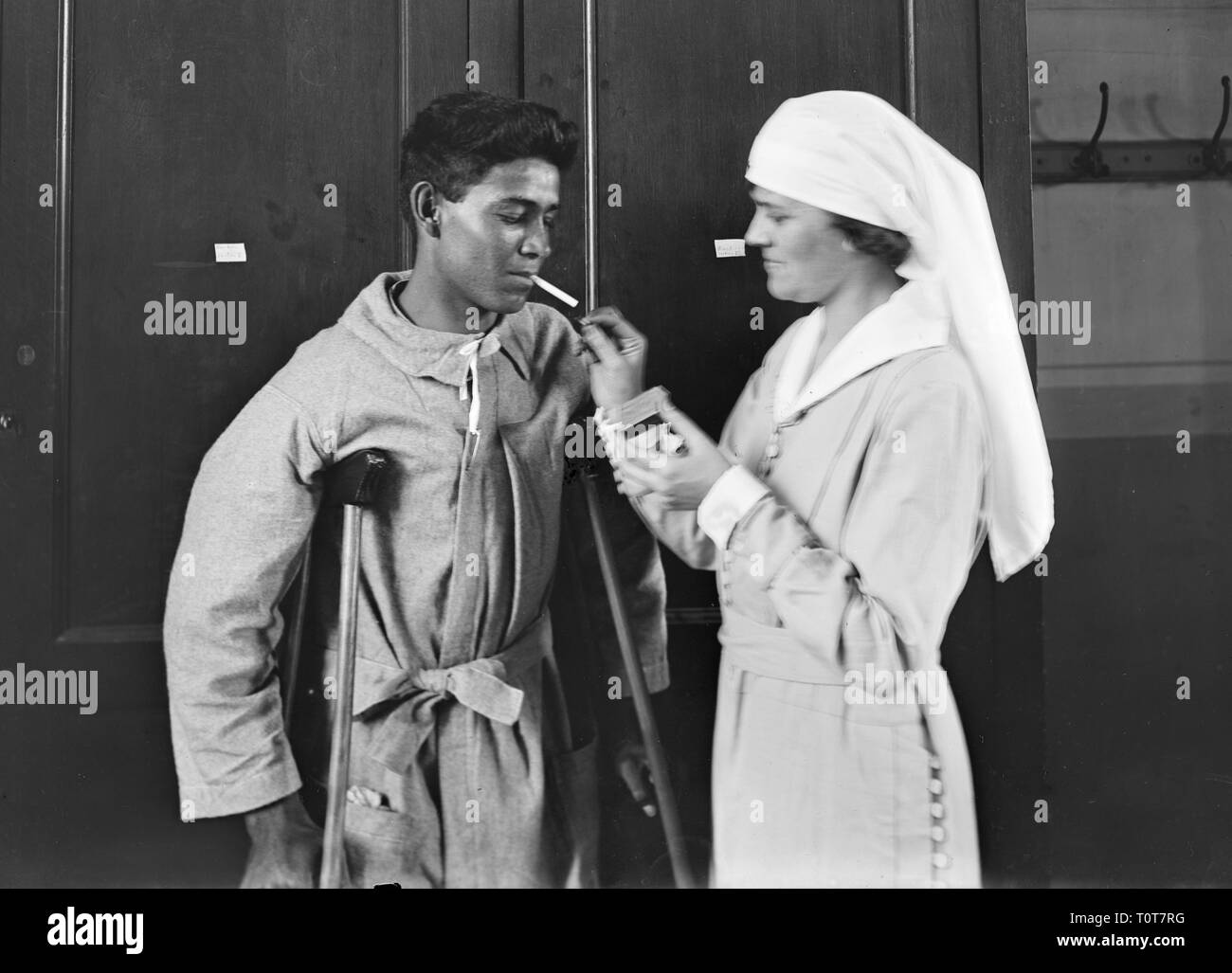 Krankenschwester leuchtet eine Zigarette für einen Patienten, Mexikanische junge bekommt einen Rauch aus dem Amerikanischen Roten Kreuz Dame 1918 Stockfoto