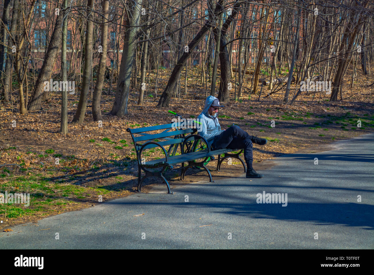 Der Mensch ist auf der Bank sitzen und sein Smartphone Kontrolle im Prospect Park im Frühling, 2019 Stockfoto