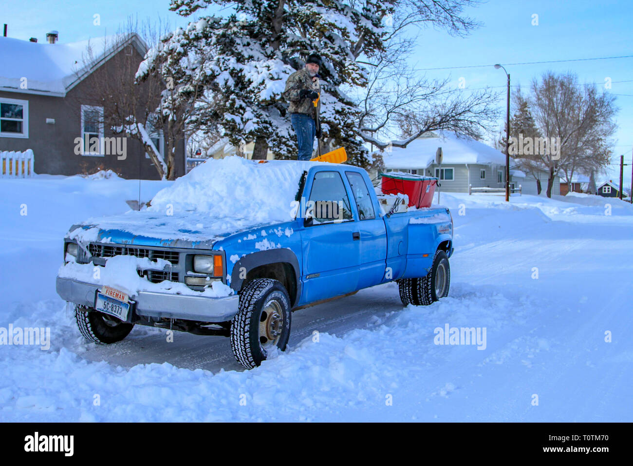 Mann an der Spitze von Chevrolet truck Schneeschaufeln nach einem grossen Februar Winter Schnee Sturm, Helena, Montana, USA Stockfoto