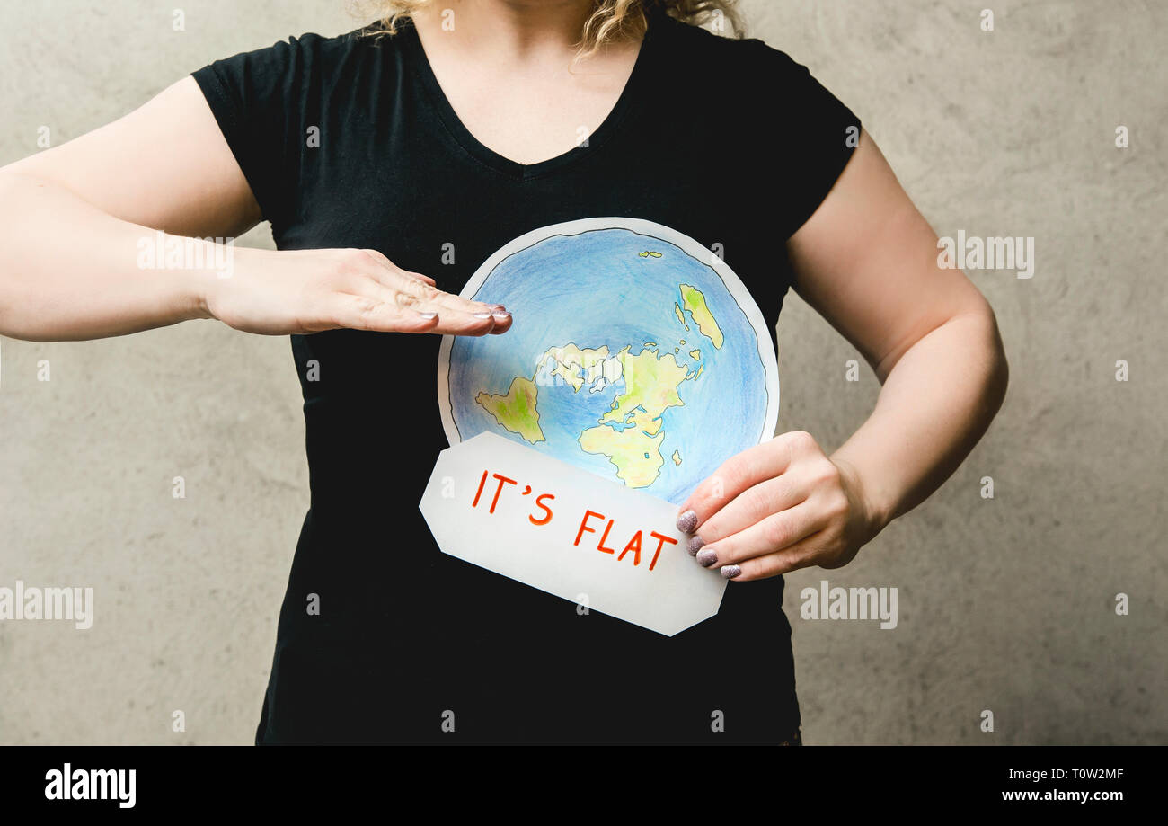 Flache Earther Konzept. Person, die glaubt, dass die Erde flach ist. Anonyme Frau mit flachen Erde Modell vor der Körper mit Text: Es ist flach. Iso Stockfoto