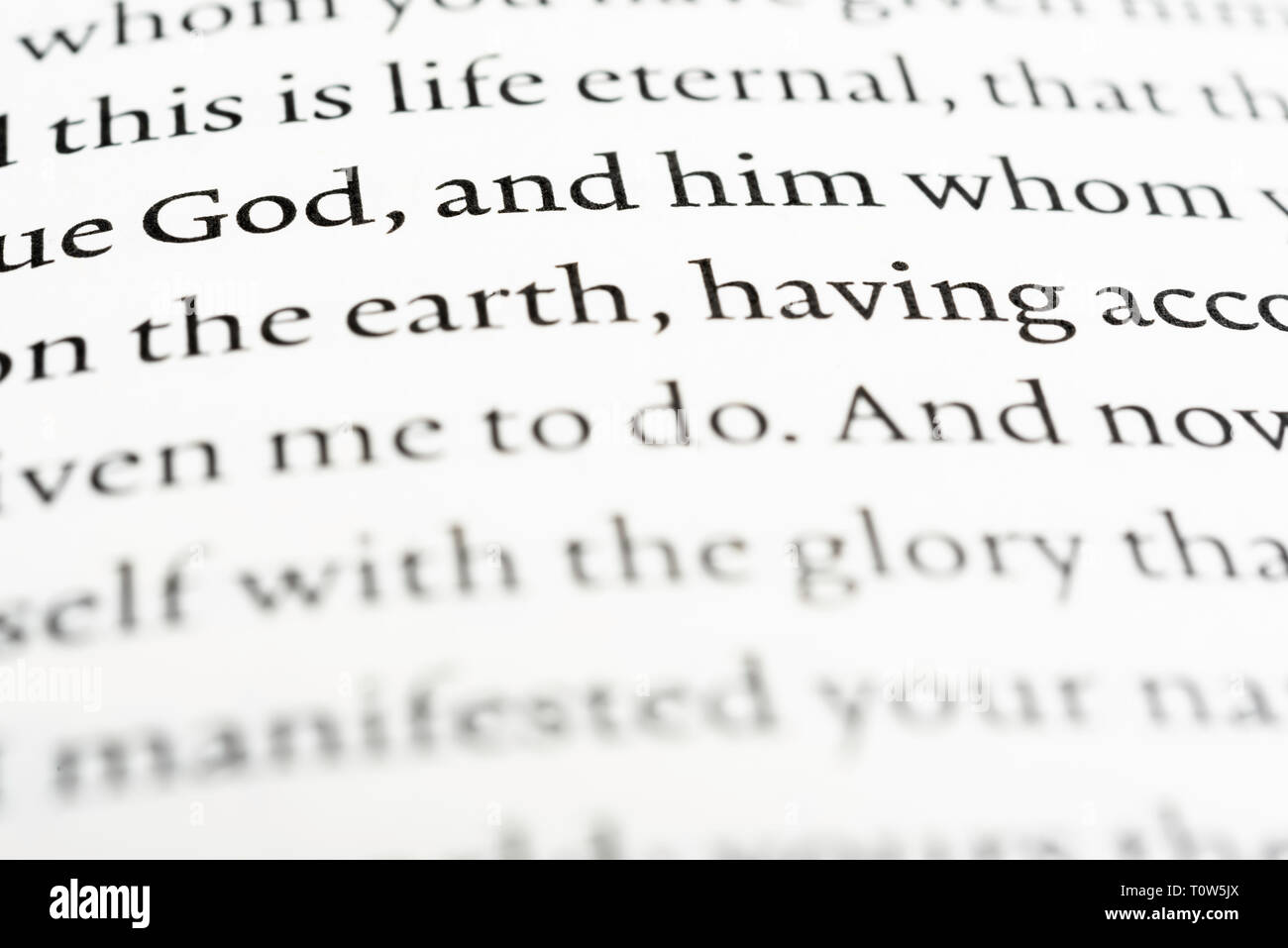 Eine extreme Nahaufnahme oder eine Makroaufnahme einer gedruckten Textbibelseite mit dem prominenten Wort Gott oder Jesus Christus. Stockfoto