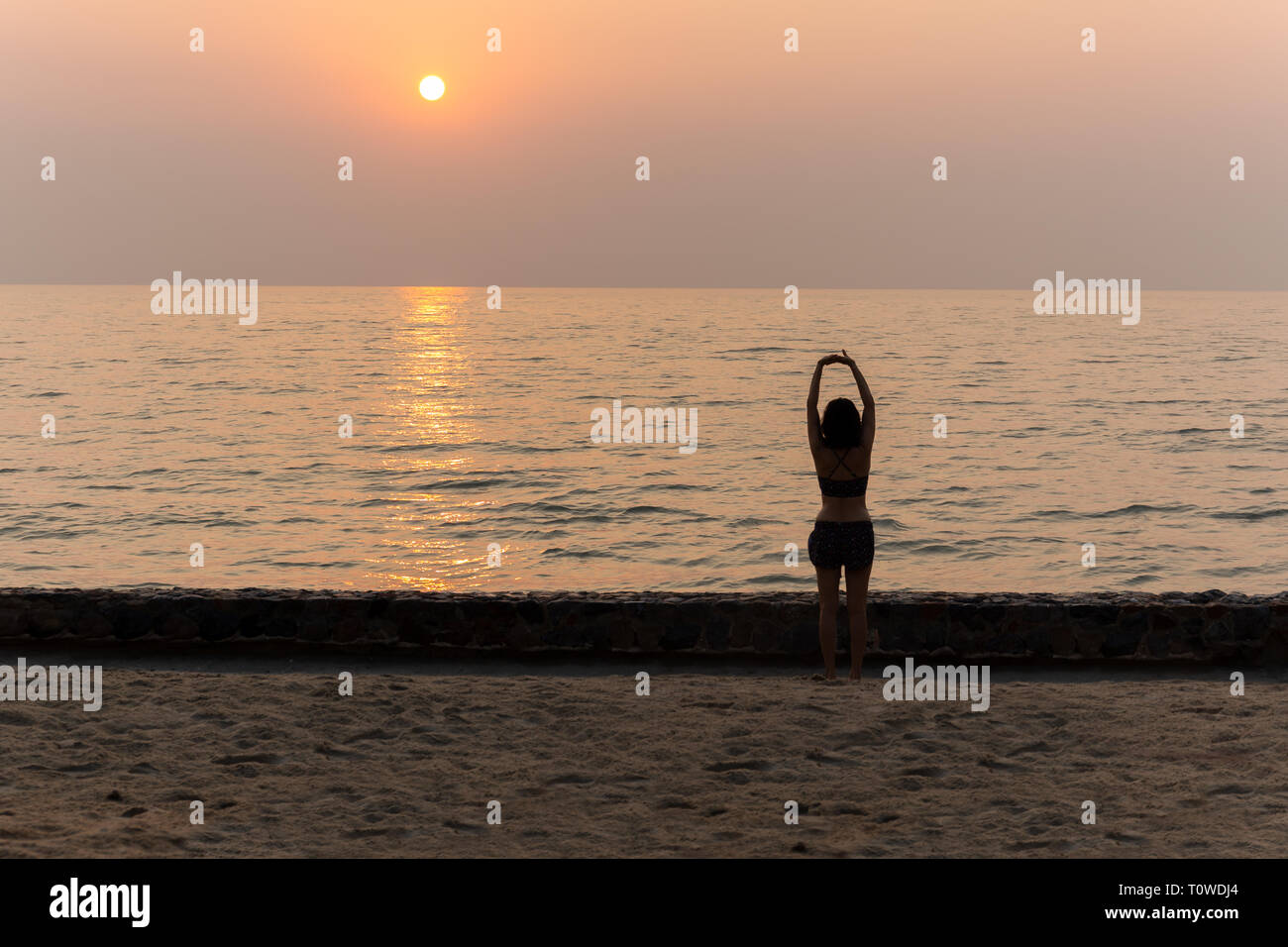 Frau Yoga bei Sonnenuntergang am Strand im Urlaub. Stockfoto