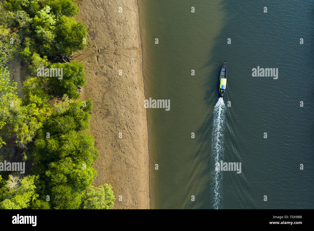 Ansicht von oben, beeindruckende Luftaufnahme eines traditionellen Long tail Boot, Segel auf einem Fluss durch einen grünen tropischen Wald fließt. Krabi, Thailand. Stockfoto