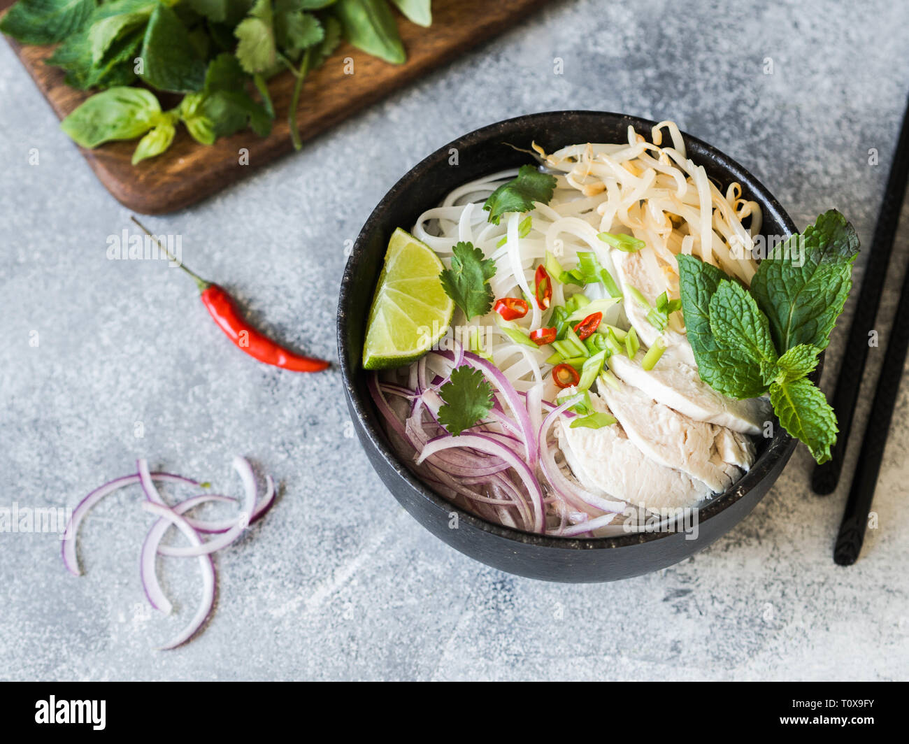 Traditionelle vietnamesische Suppe-Pho Ga in schwarz Schüssel mit Huhn und Reis Nudeln, Minze und cilantro, grüne und rote Zwiebel, Paprika, Sojasprossen und Kalk Stockfoto
