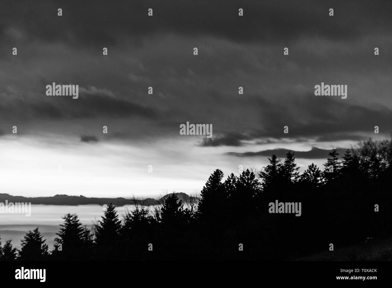 Bäume Silhouetten gegen den Himmel in der Dämmerung, mit Bergen Schichten im Hintergrund Stockfoto