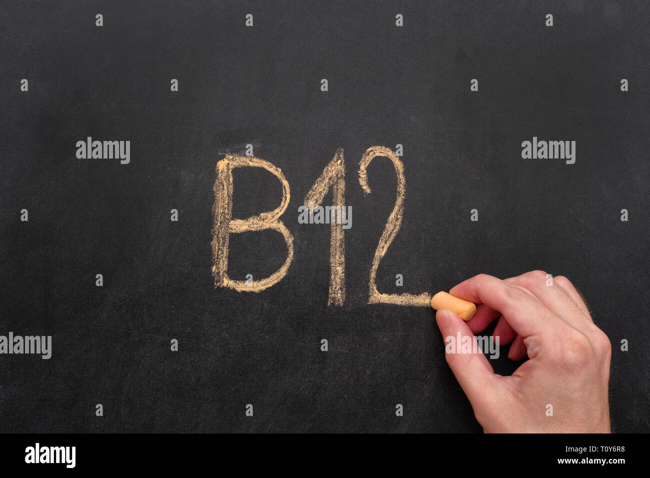 Mann schreiben Wort B 12 am schwarzen Brett. Vitamin-B12-Konzept. Close Up. Stockfoto