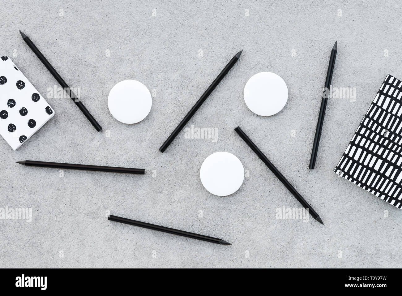 Leere Abzeichen und scharfe schwarze Bleistifte auf grauem Beton Hintergrund. Stockfoto