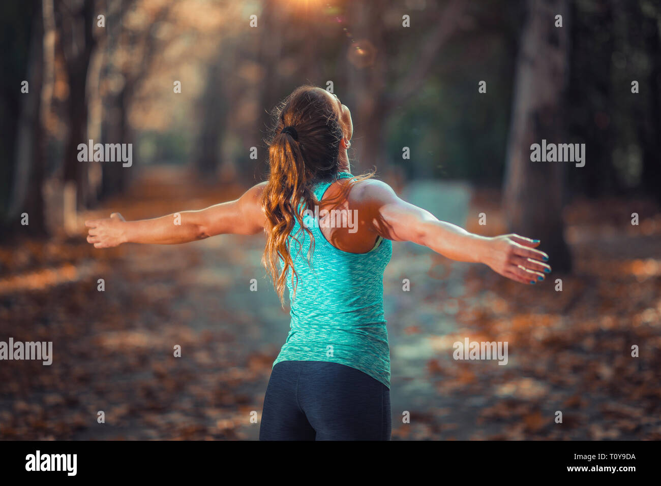 Frau Training im Freien, in öffentlichen Park. Stehend mit erhobenen Armen. Stockfoto