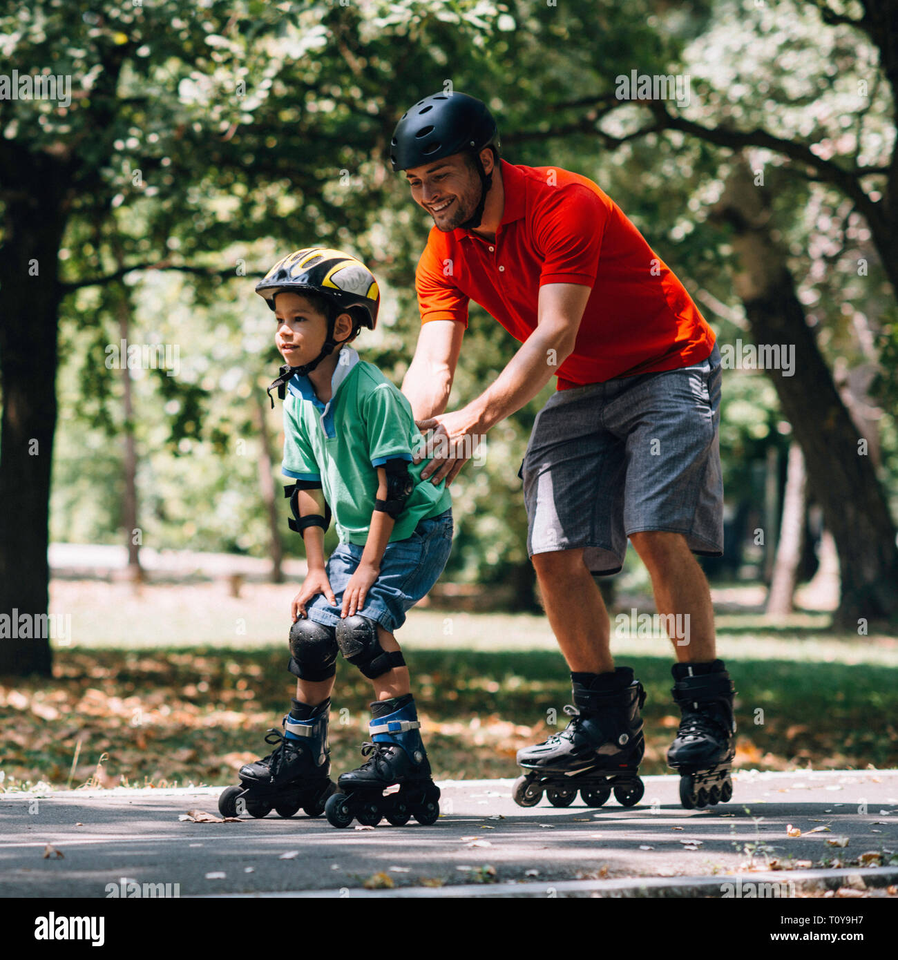 Vater lehre Sohn Skaten in Park. Stockfoto Vater lehre Sohn Skaten in Park. Stockfoto